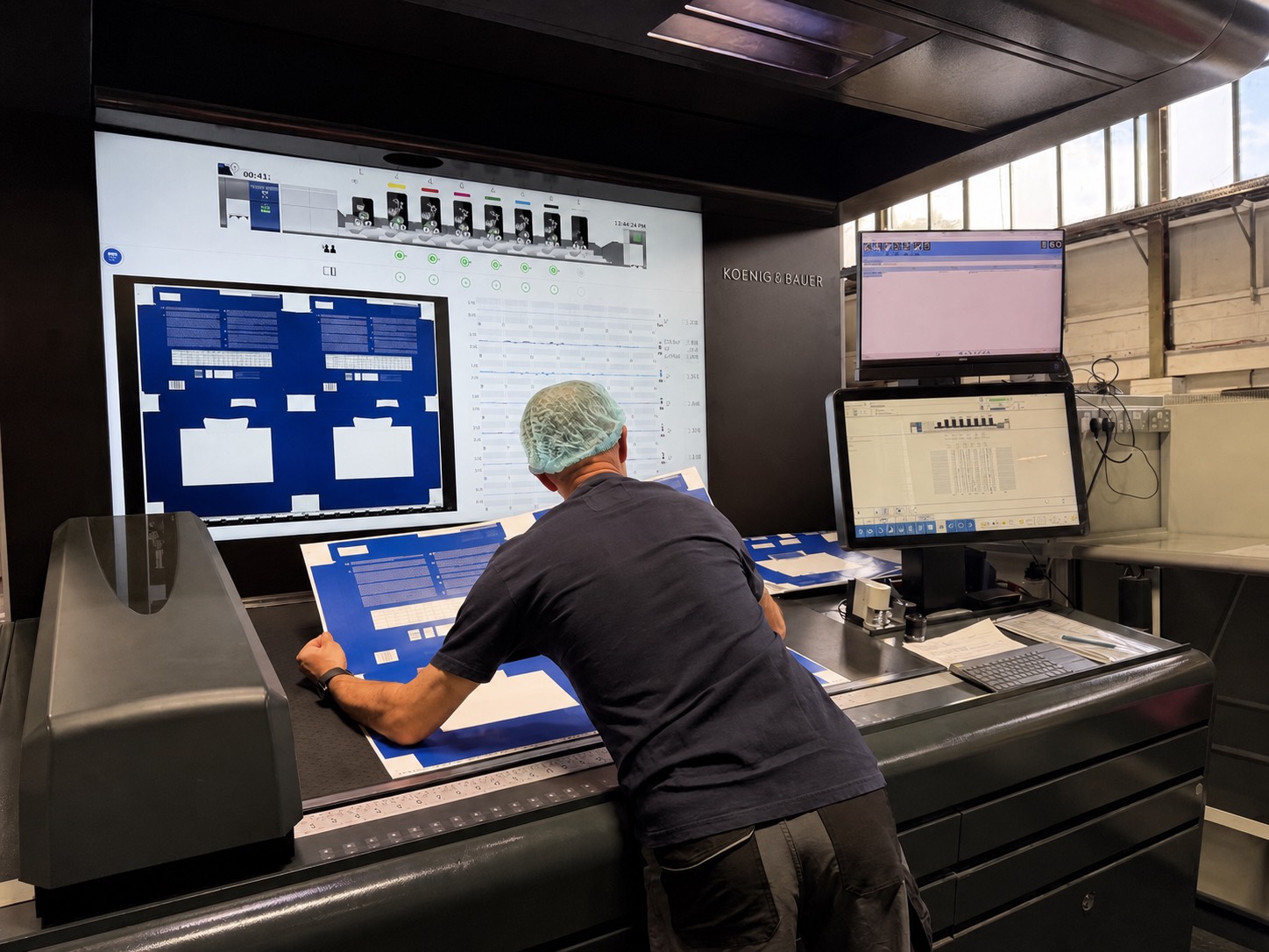 A Carton-Pro press minder checking printed sheets against the plate at the Koenig and Bauer press console in Peterborough
